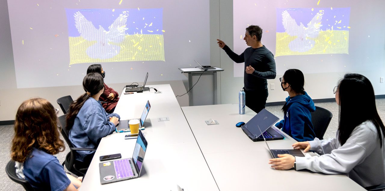 Ira Greenberg teaching a creative-computation class at SMU, with his generative artwork projected on the screens